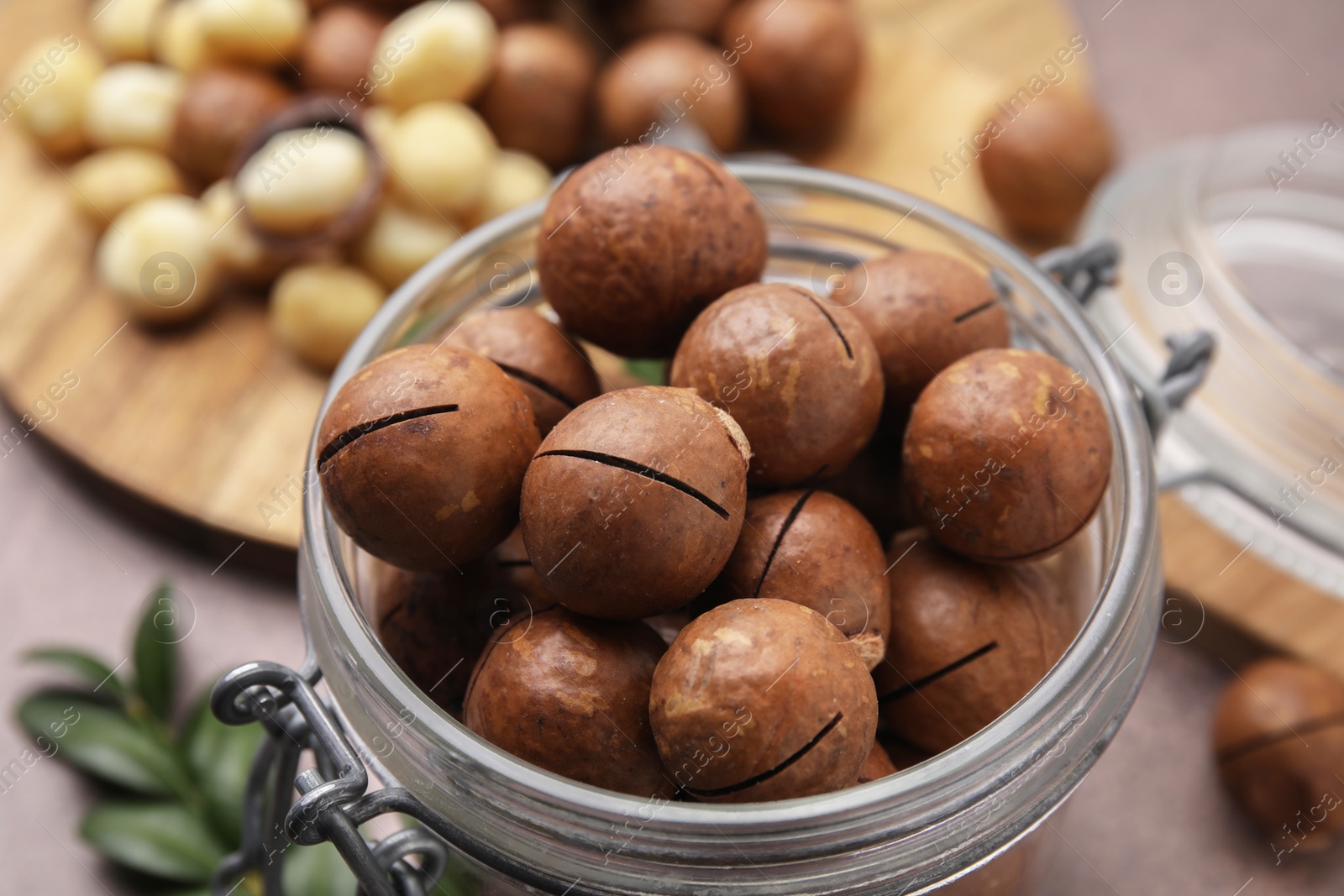 Photo of Tasty Macadamia nuts in jar on table, closeup
