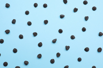 Photo of Delicious dark chocolate chips on light blue background, top view