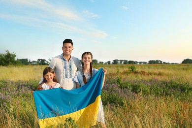 Photo of Family holding national flag of Ukraine in field. Space for text