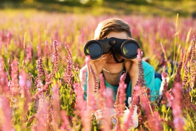 Teenage boy with binoculars in field. Summer camp