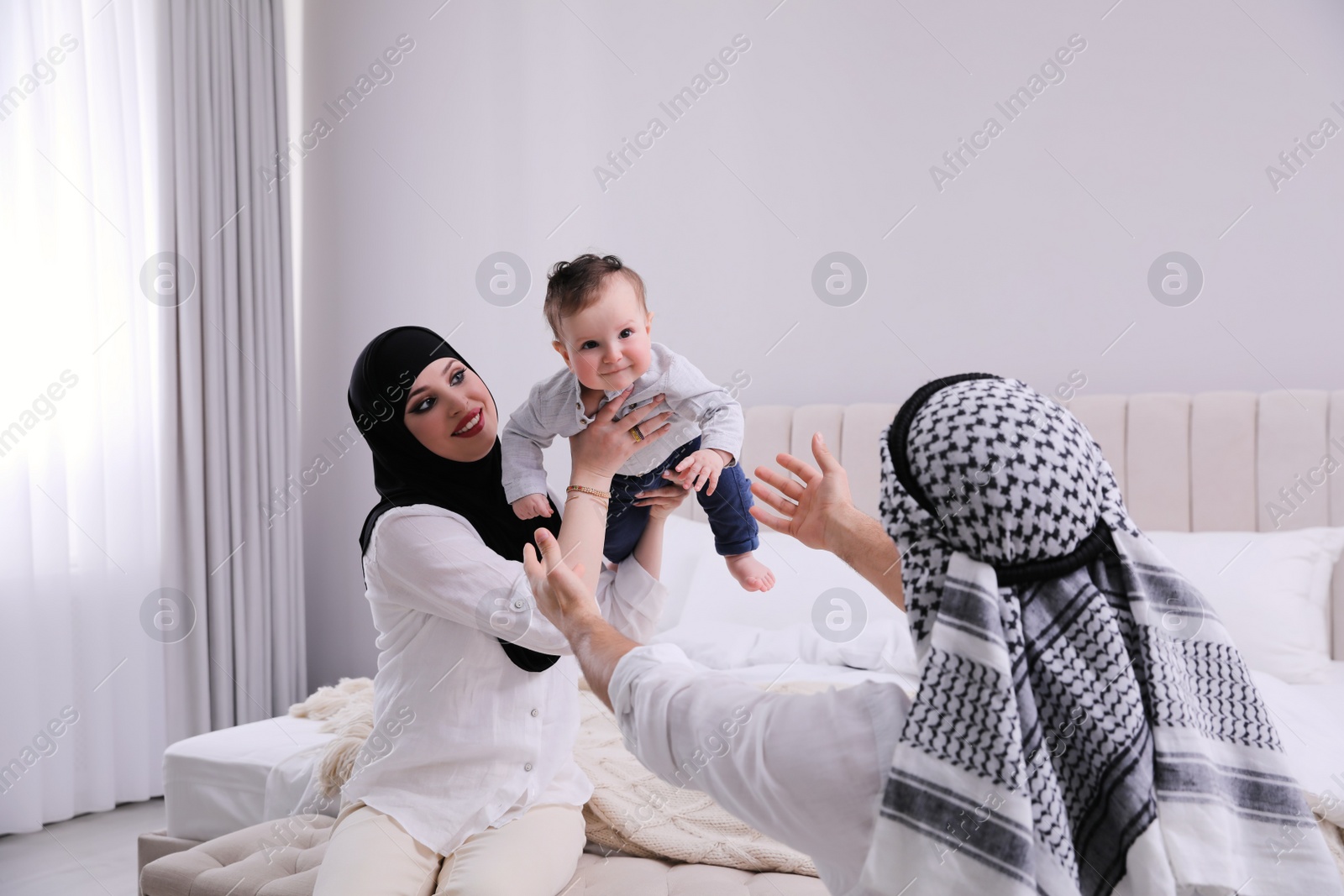 Photo of Happy Muslim family with little son in bedroom