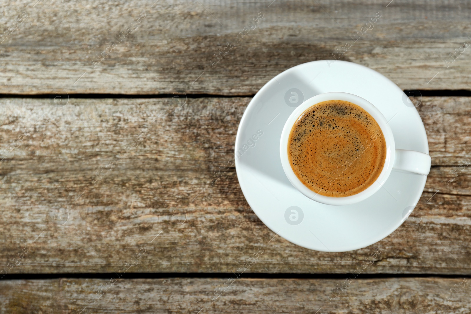 Photo of Cup of tasty coffee on wooden table, top view. Space for text