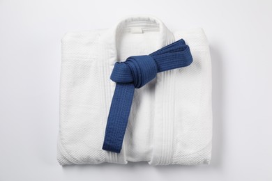 Photo of Blue karate belt and kimono on white background, top view