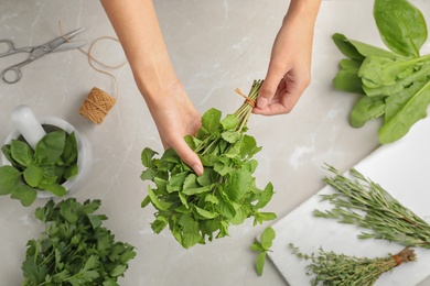 Woman holding mint over table, top view. Fresh herbs