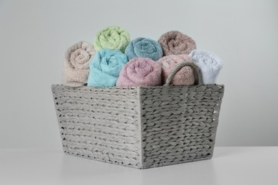 Wicker basket with clean soft towels on light background