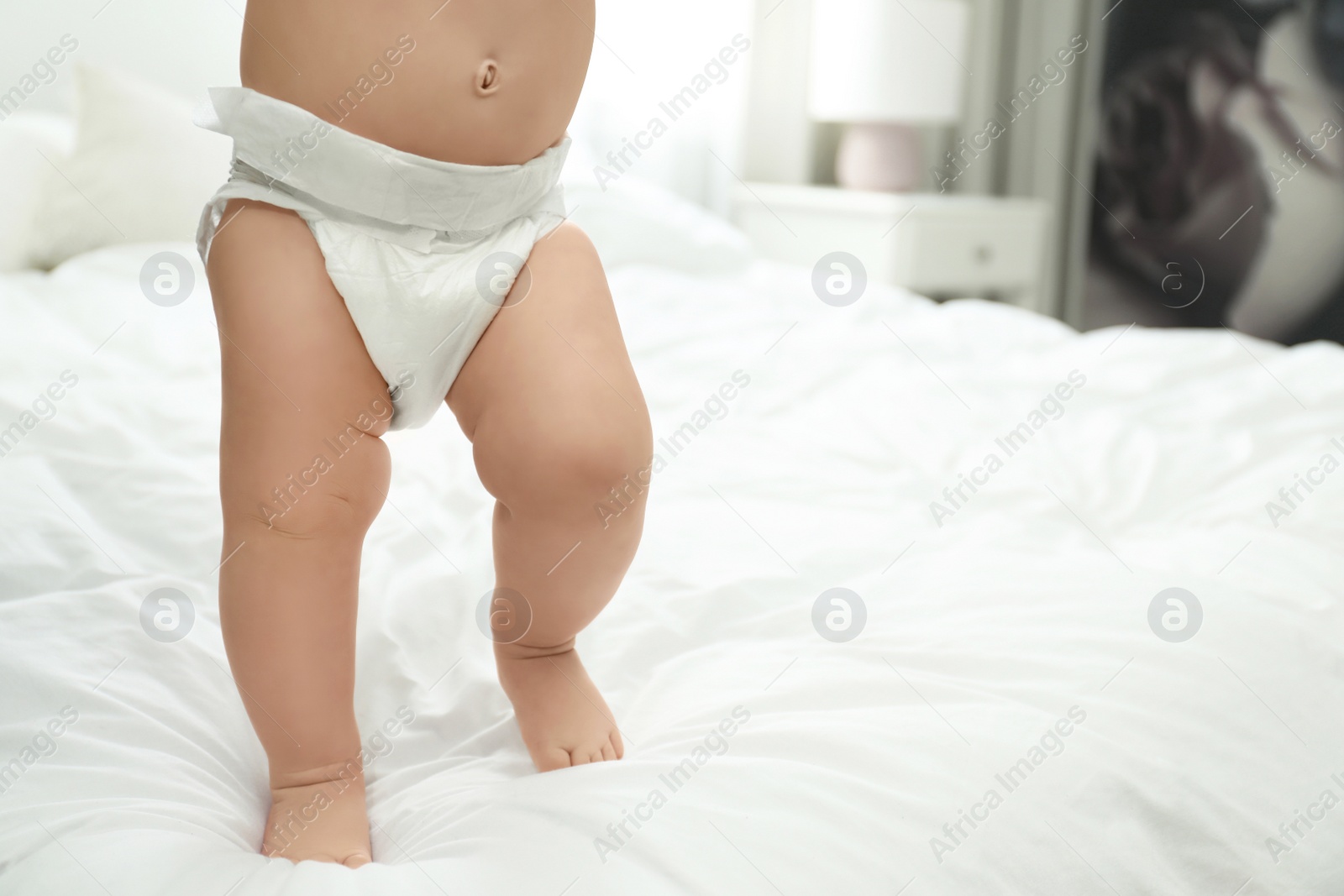 Photo of Cute little baby in diaper on bed, closeup. Space for text