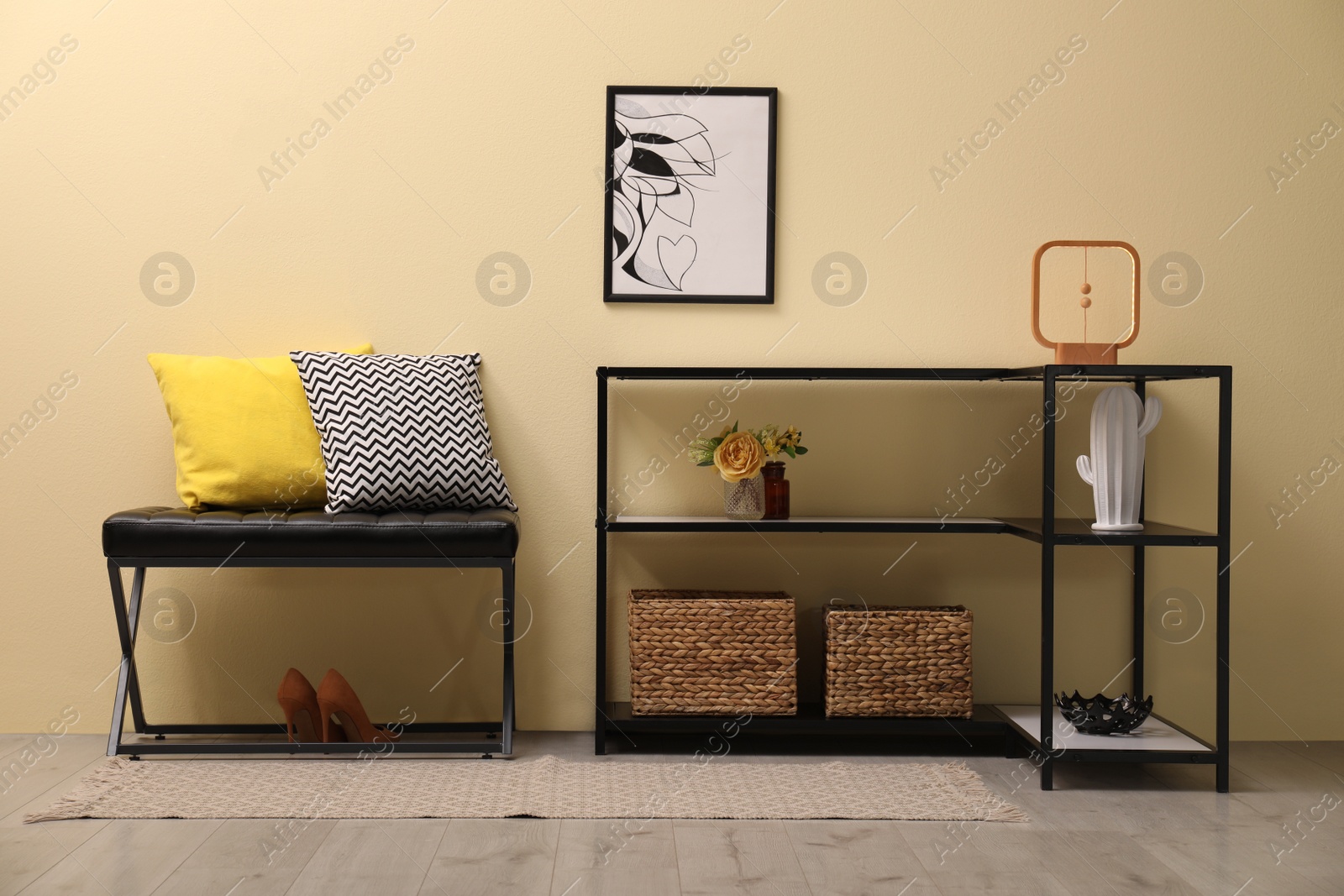 Photo of Console table with decor and bench near beige wall in hallway. Interior design