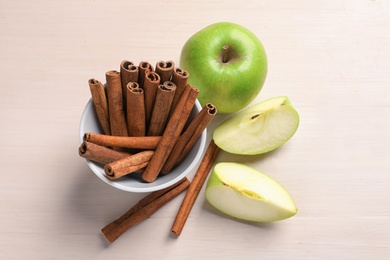 Fresh apples and cinnamon sticks on table