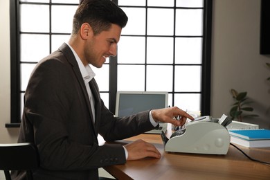 Man using banknote counter at wooden table indoors