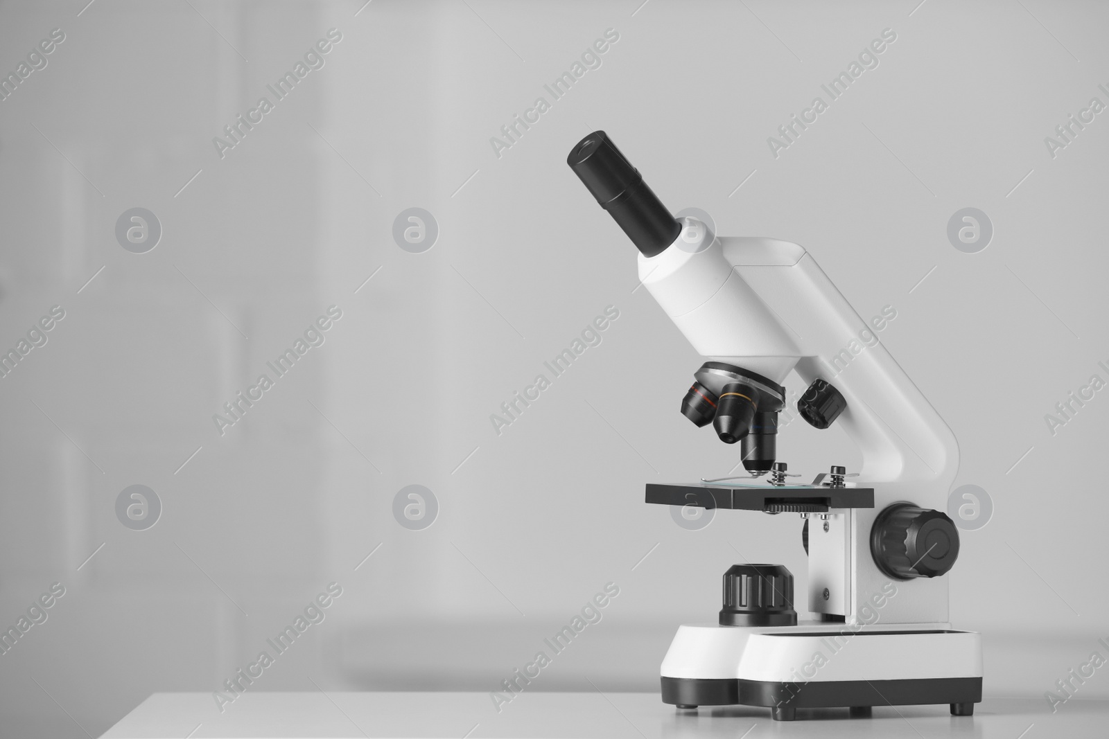 Photo of Modern microscope on table indoors. Space for text