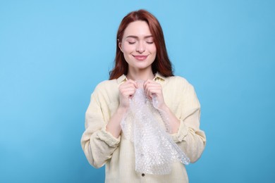 Woman popping bubble wrap on turquoise background. Stress relief