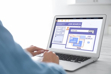 Image of Woman working with modern laptop at white table indoors, closeup. Job search