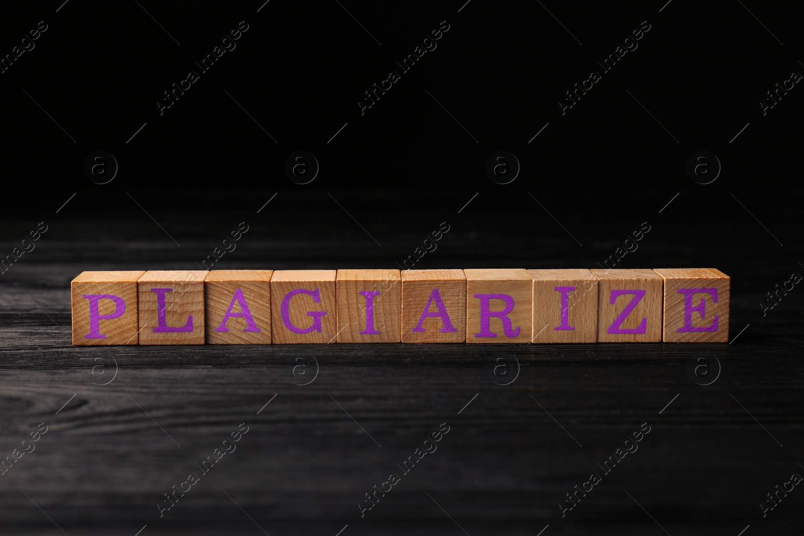 Photo of Wooden cubes with word Plagiarize on black table