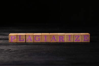 Wooden cubes with word Plagiarize on black table
