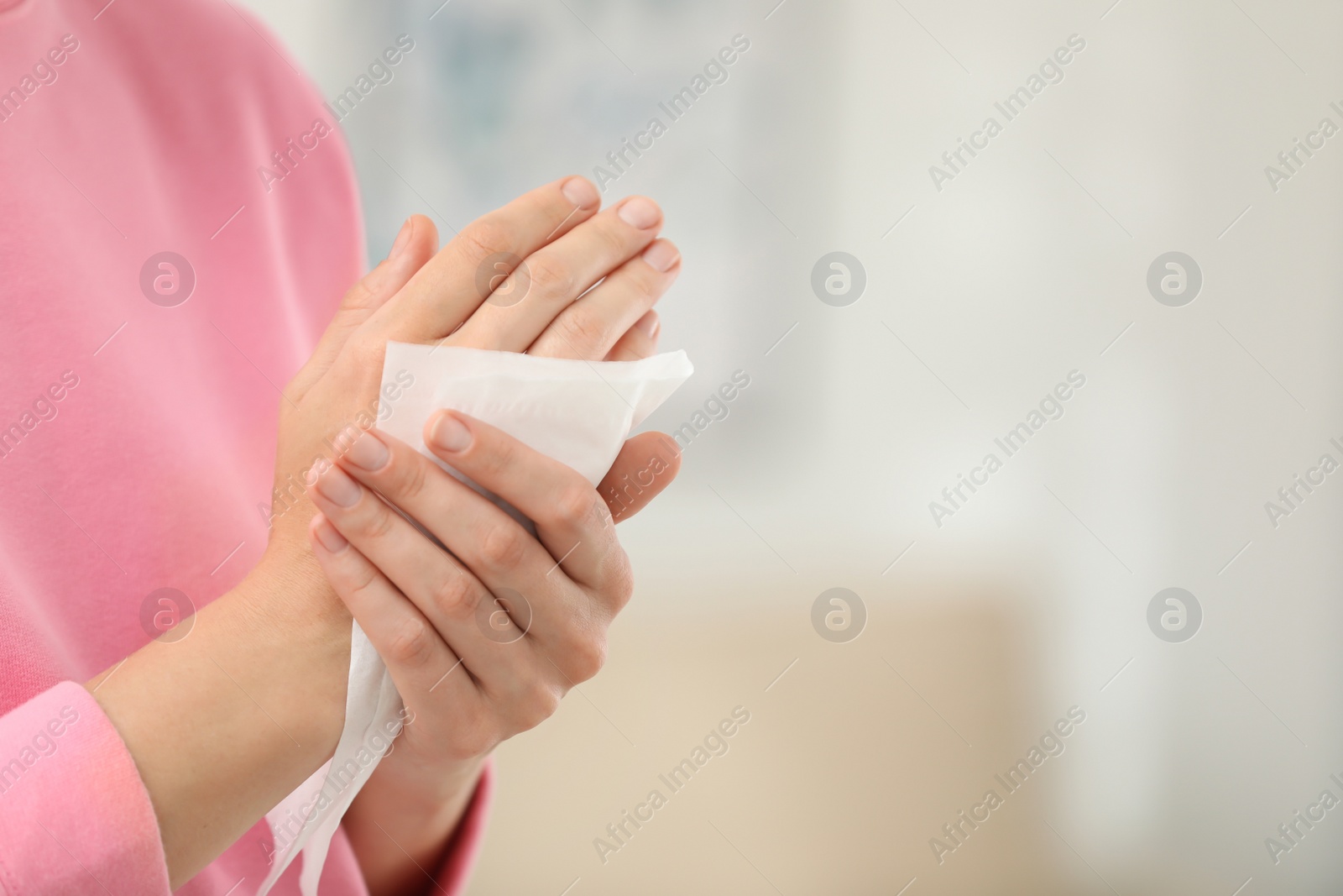 Photo of Woman cleaning hands with paper tissue on blurred background, closeup. Space for text