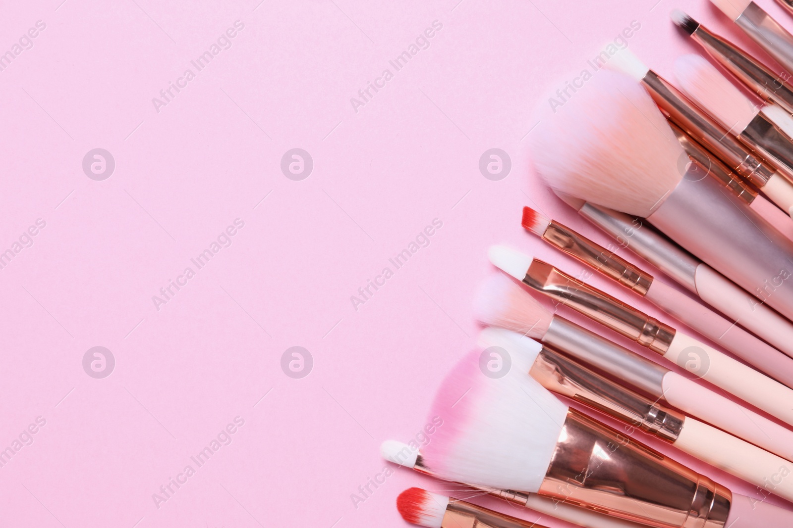 Photo of Many different makeup brushes on pink background, flat lay. Space for text