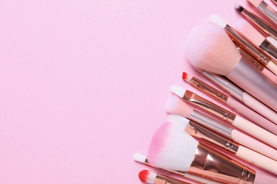 Photo of Many different makeup brushes on pink background, flat lay. Space for text