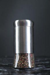 Pepper shaker on dark marble table, closeup