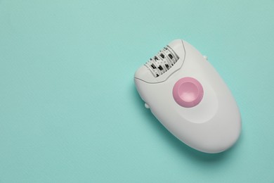 Photo of Modern epilator on turquoise background, top view. Space for text