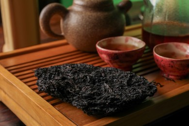 Broken disc shaped pu-erh tea on wooden tray, closeup