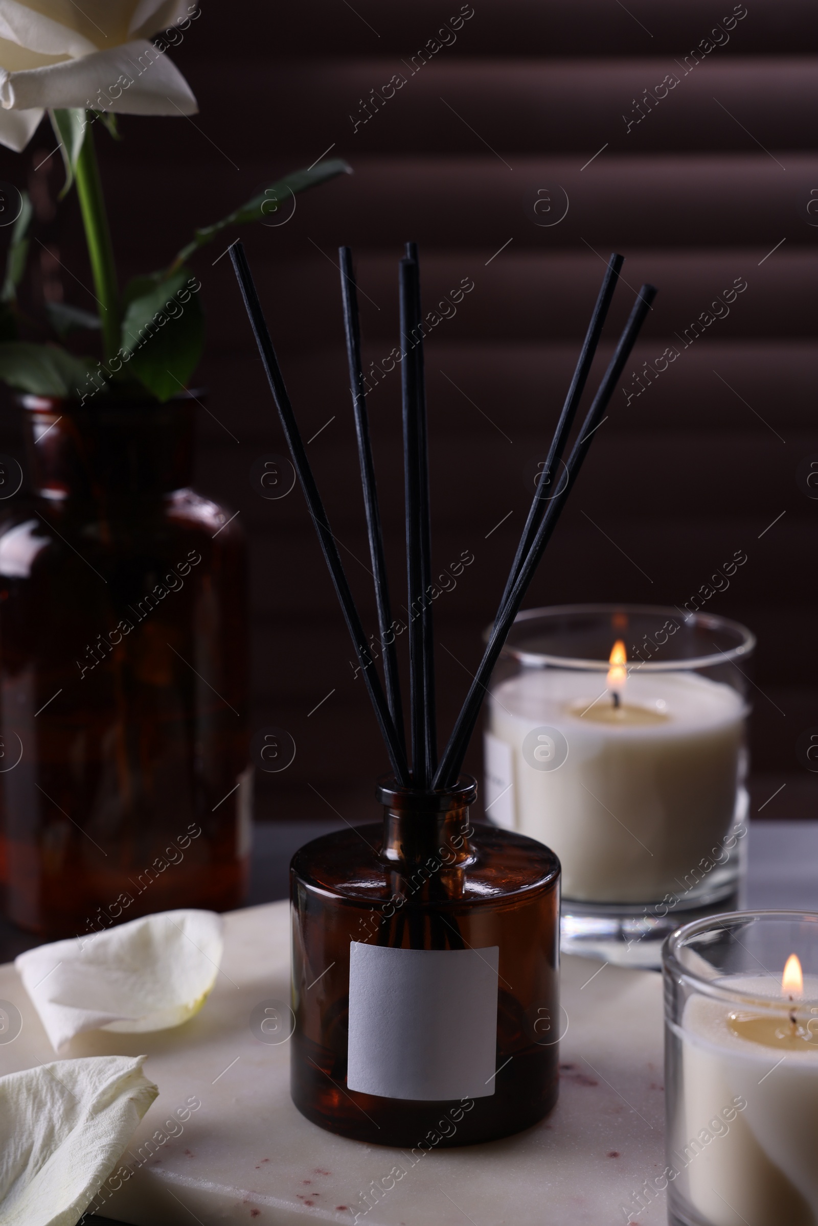 Photo of Aromatic reed air freshener and burning candles on white board near window