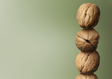 Stacked walnuts on green gradient background, space for text