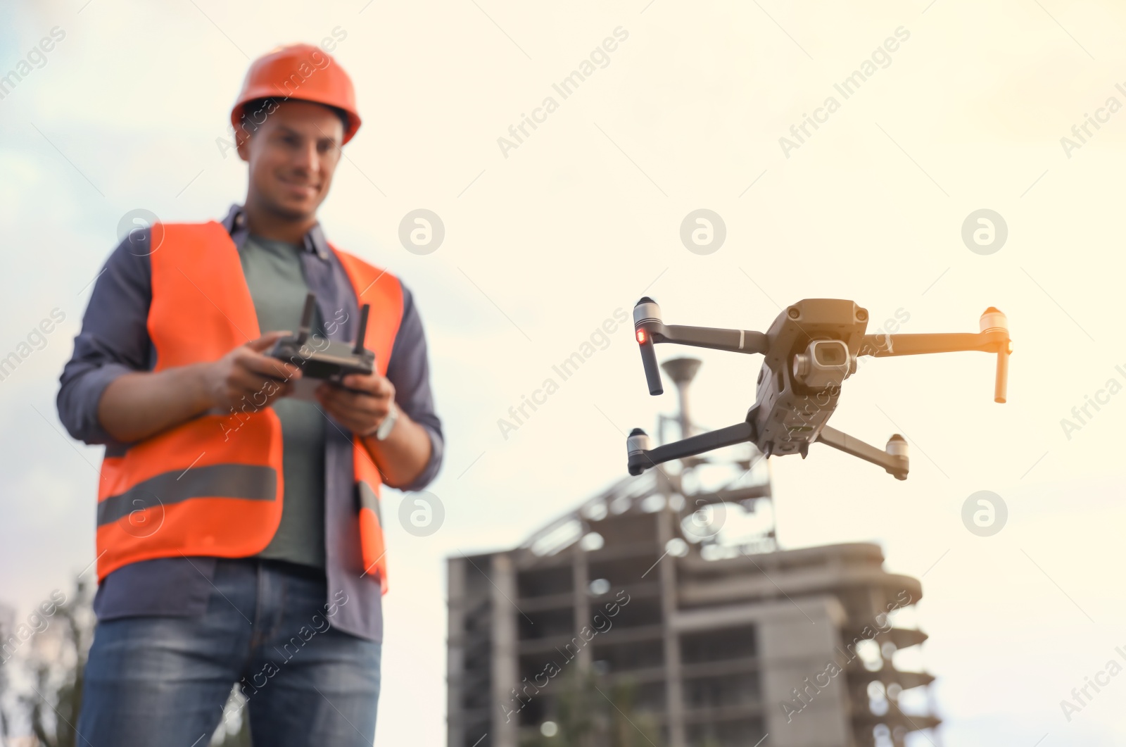 Photo of Builder operating drone with remote control at construction site, focus on quadcopter. Aerial survey