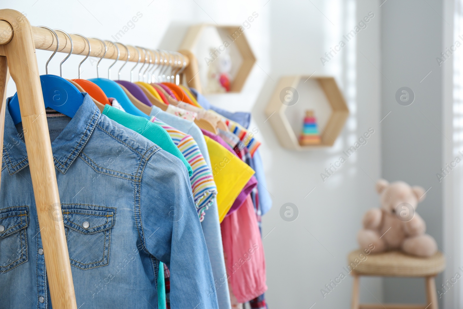 Photo of Different child's clothes hanging on rack in room, closeup