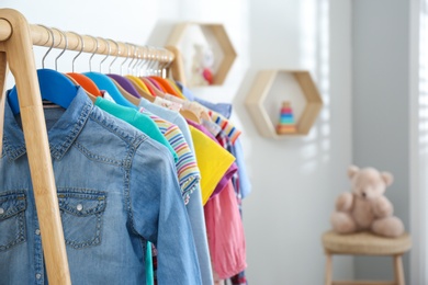 Different child's clothes hanging on rack in room, closeup