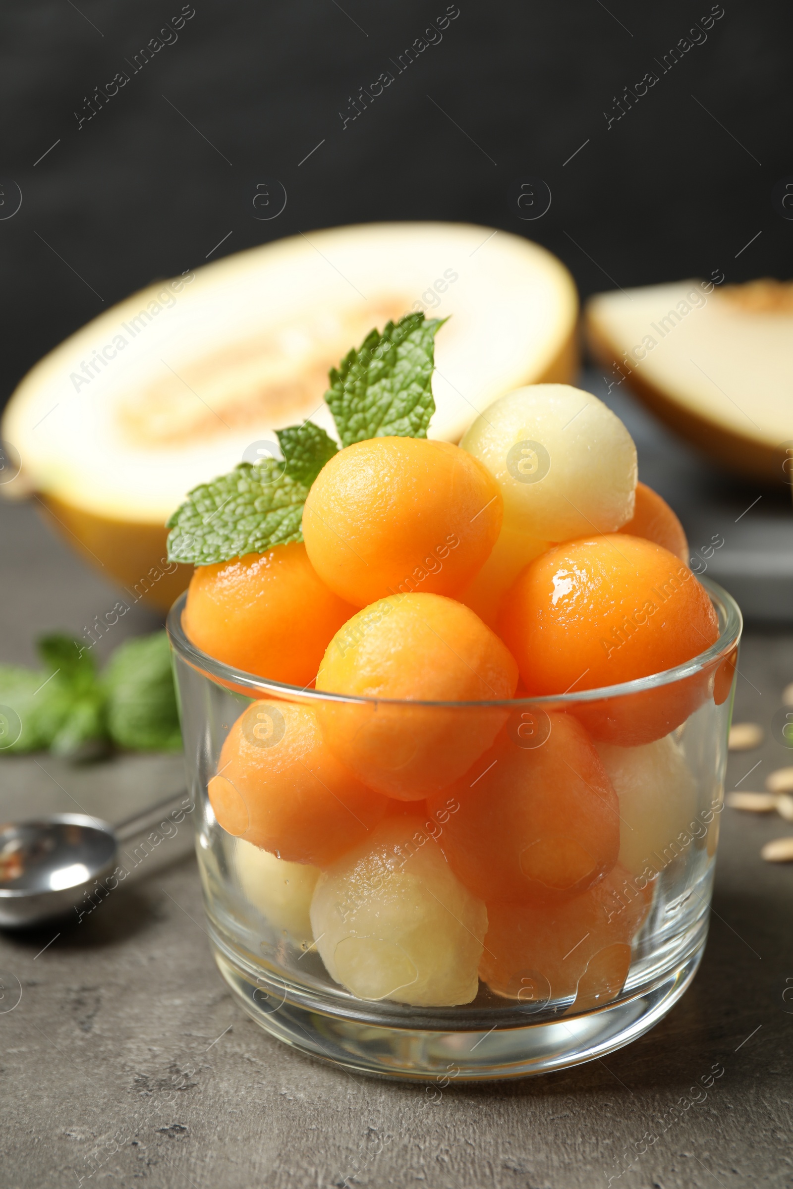 Photo of Melon balls and mint in glass on grey table, closeup