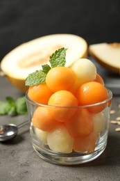 Photo of Melon balls and mint in glass on grey table, closeup