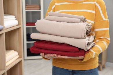 Photo of Woman with stack of bed linens in shop, closeup