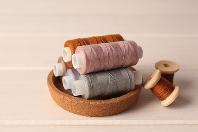 Photo of Set of color sewing threads on white wooden table