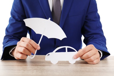 Photo of Insurance agent with paper cutout umbrella and car at table