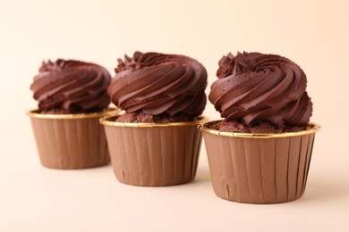 Photo of Delicious chocolate cupcakes on beige background, closeup