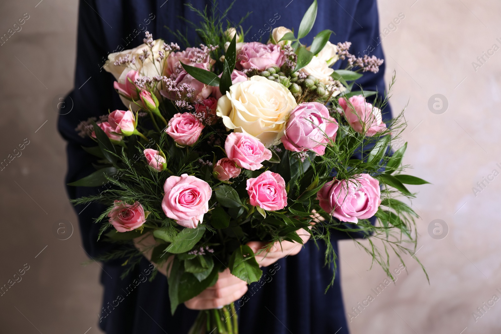 Photo of Woman with bouquet of beautiful roses on beige background, closeup