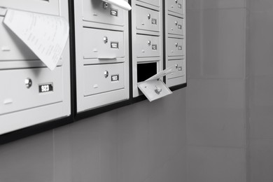 Photo of Closed grey metal mailboxes with receipts indoors