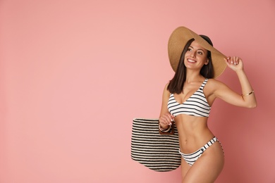 Photo of Pretty sexy woman with slim body in stylish striped bikini on coral background, space for text