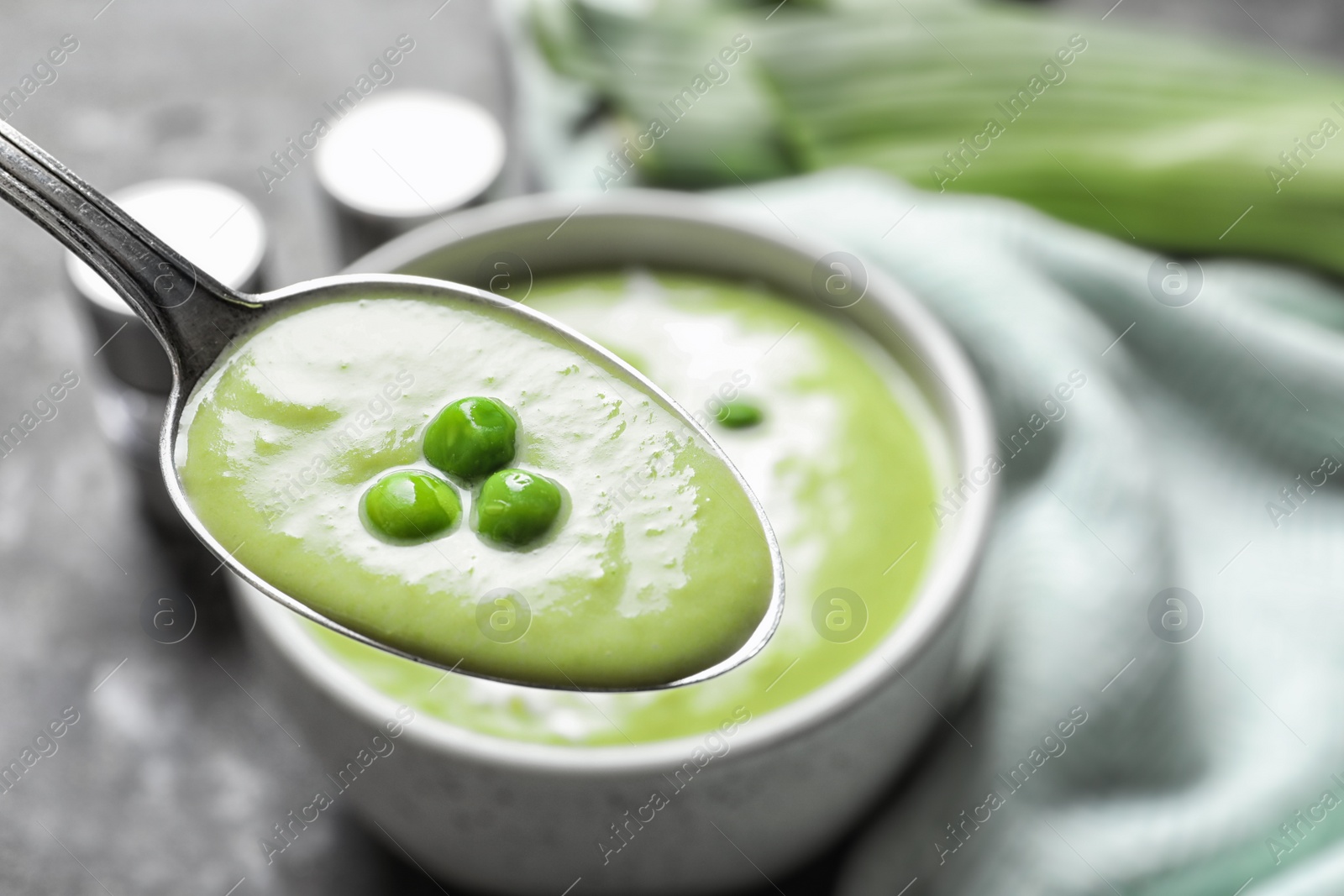 Photo of Spoon with fresh vegetable detox soup made of green peas on blurred background, closeup