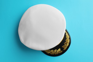 Photo of Peaked cap with accessories on light blue background, top view