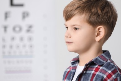 Photo of Cute little boy against vision test chart