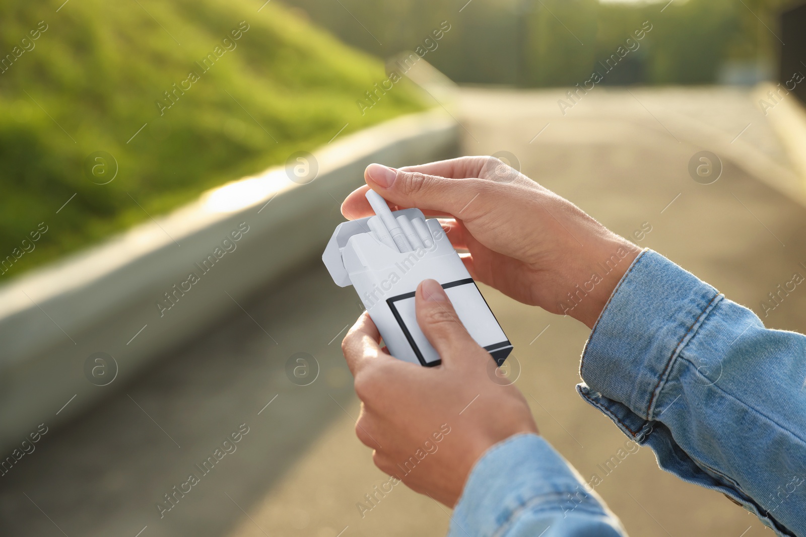 Photo of Woman taking cigarette out of pack outdoors, closeup. Space for text