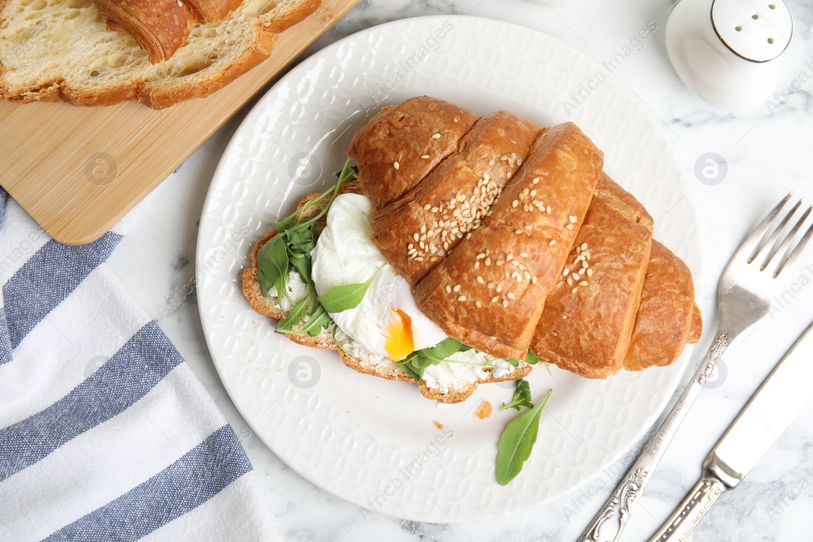 Photo of Delicious croissant with arugula and egg on white marble table, flat lay