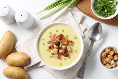 Tasty potato soup with bacon in bowl served on white table, flat lay