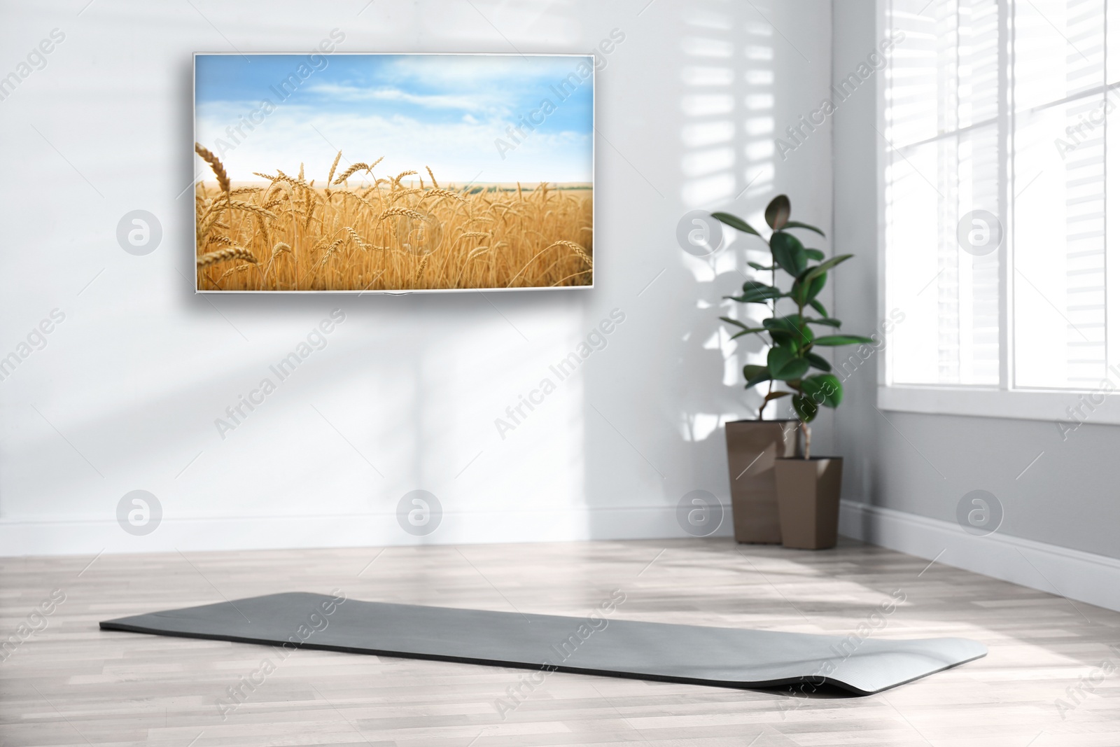 Image of Modern wide screen TV on white wall in room with yoga mat