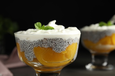 Tasty peach dessert with yogurt and chia seeds on black background, closeup