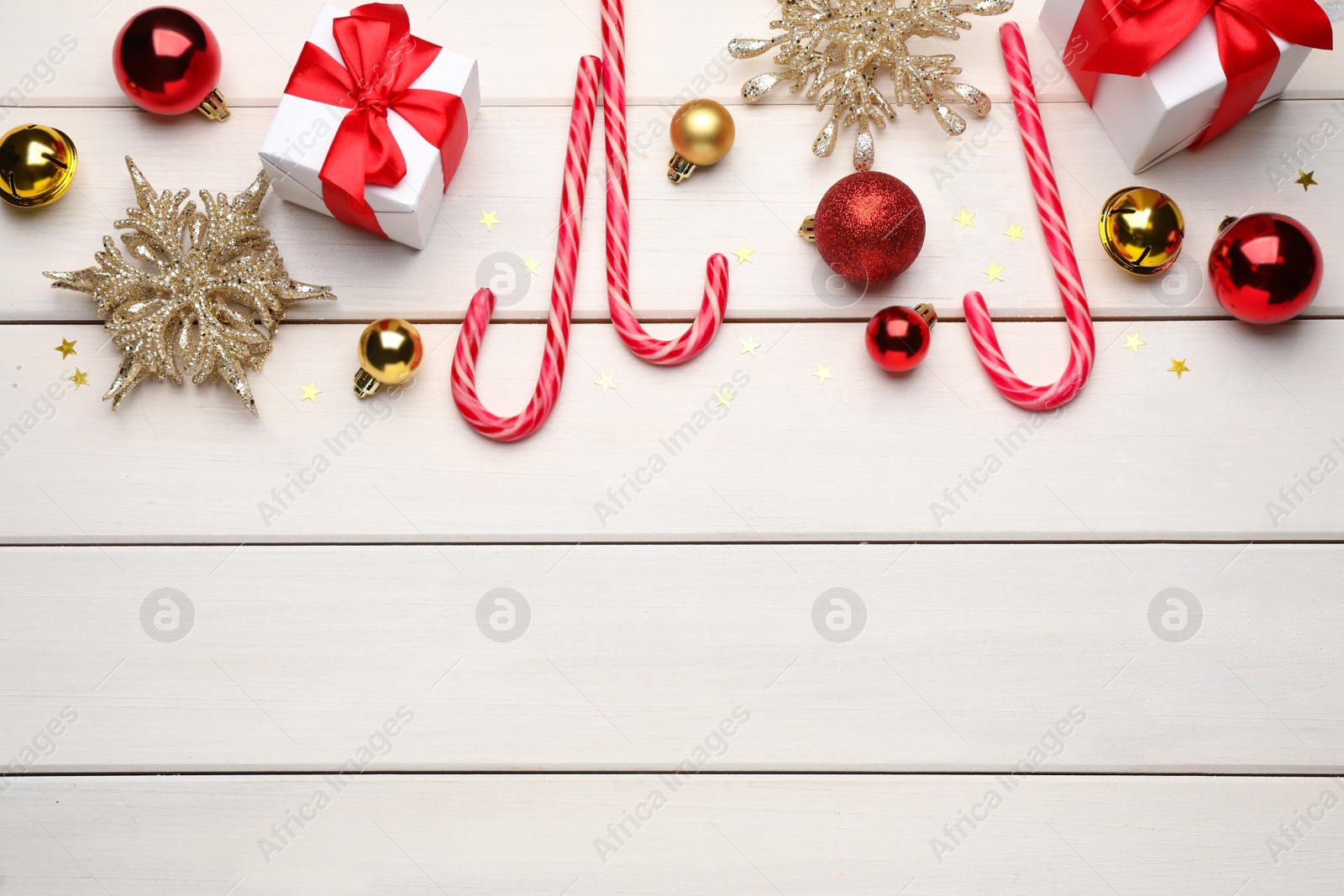 Photo of Flat lay composition with tasty candy canes and Christmas decor on white wooden table, space for text