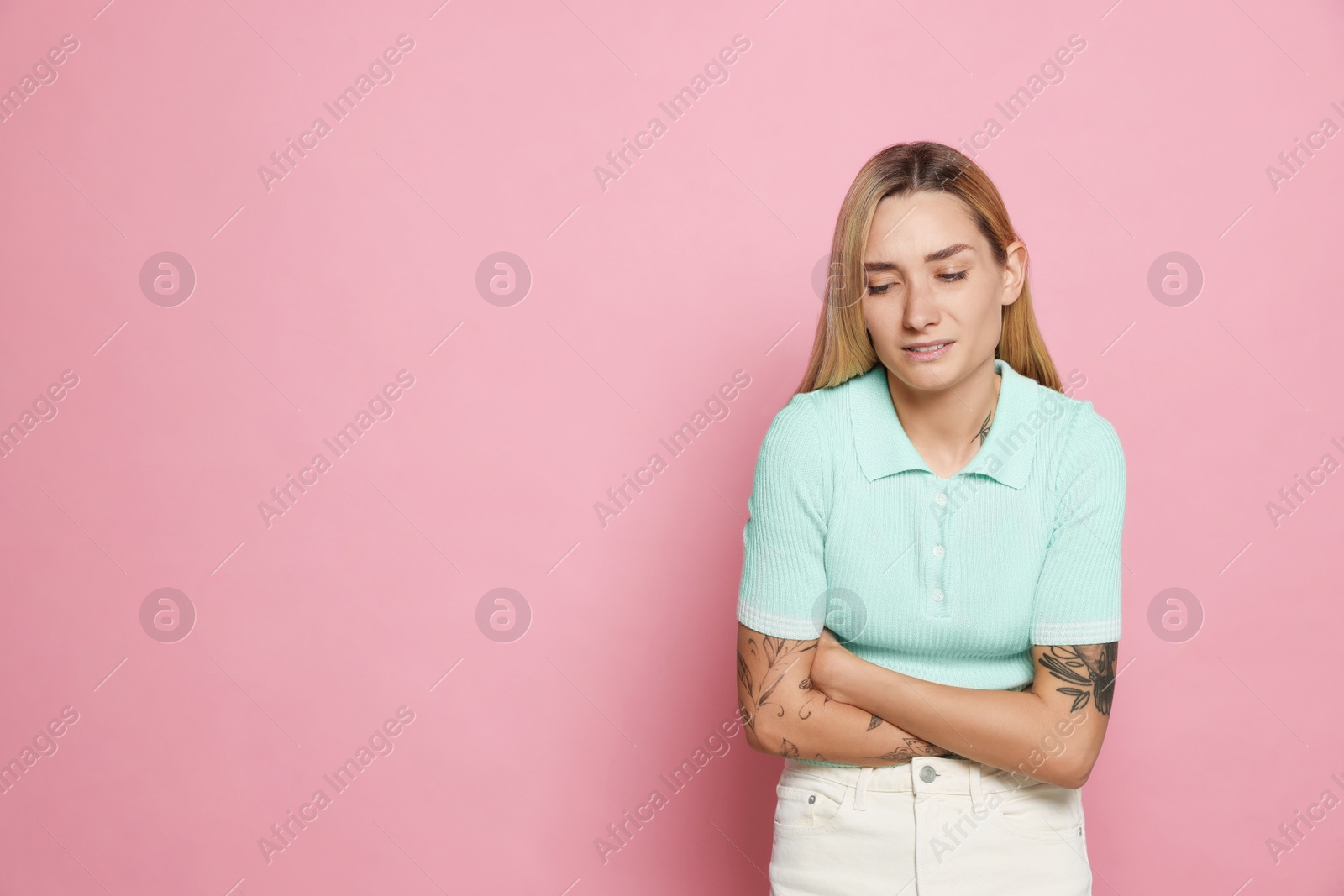 Photo of Young woman suffering from menstrual pain on pink background, space for text