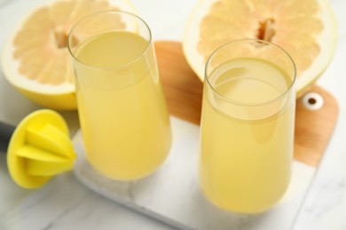 Photo of Glasses of fresh pomelo juice on white table, closeup