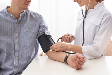 Photo of Doctor checking patient's blood pressure in hospital, closeup. Cardiology concept